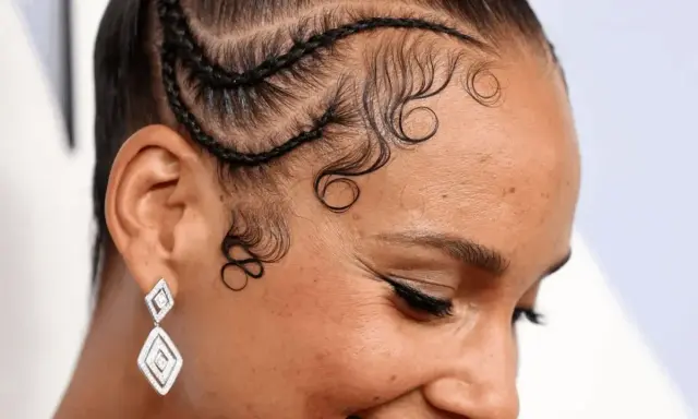 Coiffure avec des tresses et des boucles élégantes sur la hairline cheveux bouclés. Boucles artistiques encadrant le visage.