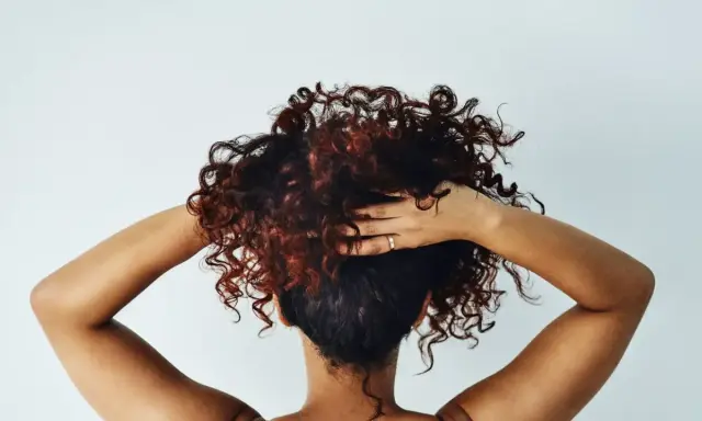 Cheveux bouclés, comme après une baignade dans l'eau salée, sont coiffés par des mains sur fond blanc.