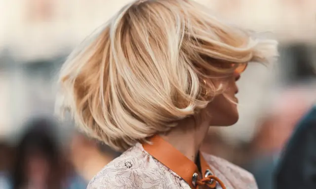 Cheveux blonds balayés par le vent, une coiffure bohème en carré, avec des mèches ondulées qui encadrent le visage.