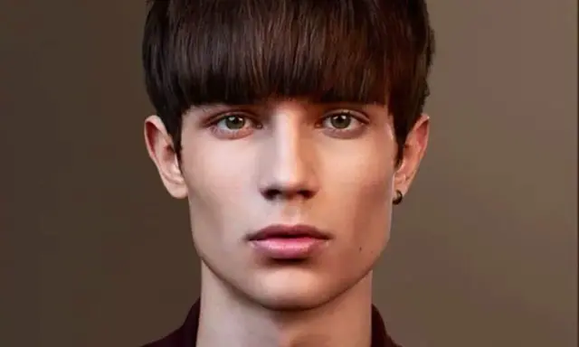 Un jeune homme au regard intense arbore une coupe au bol homme audacieuse, encadrant son visage aux traits fins.