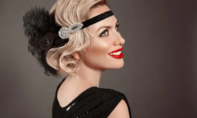 Coiffure année 20 cheveux long, avec bandeau orné de plumes et de strass. Une touche glamour pour une soirée chic.