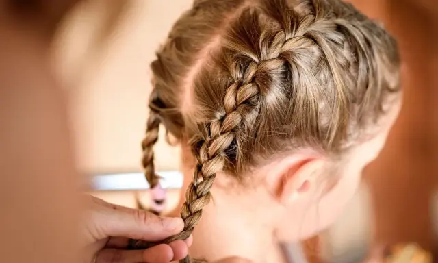 Une coiffure petite fille tresse facile, avec deux nattes bien serrées sur le dessus de la tête.