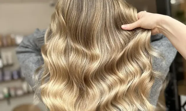 Une chevelure ondulée aux reflets dorés, un blond subtil qui joue avec la lumière.