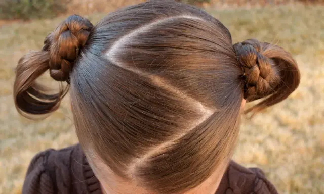 Cheveux bruns tressés en deux couettes rondes, séparés par une raie zig zag.