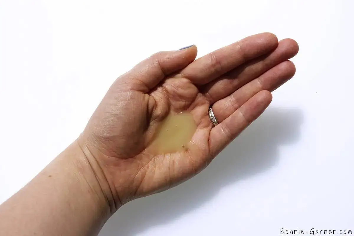 Une main ouverte tient une petite quantit&eacute; de shampoing jaune, posant la question : combien de shampoing par lavage pour un r&eacute;sultat optimal ?