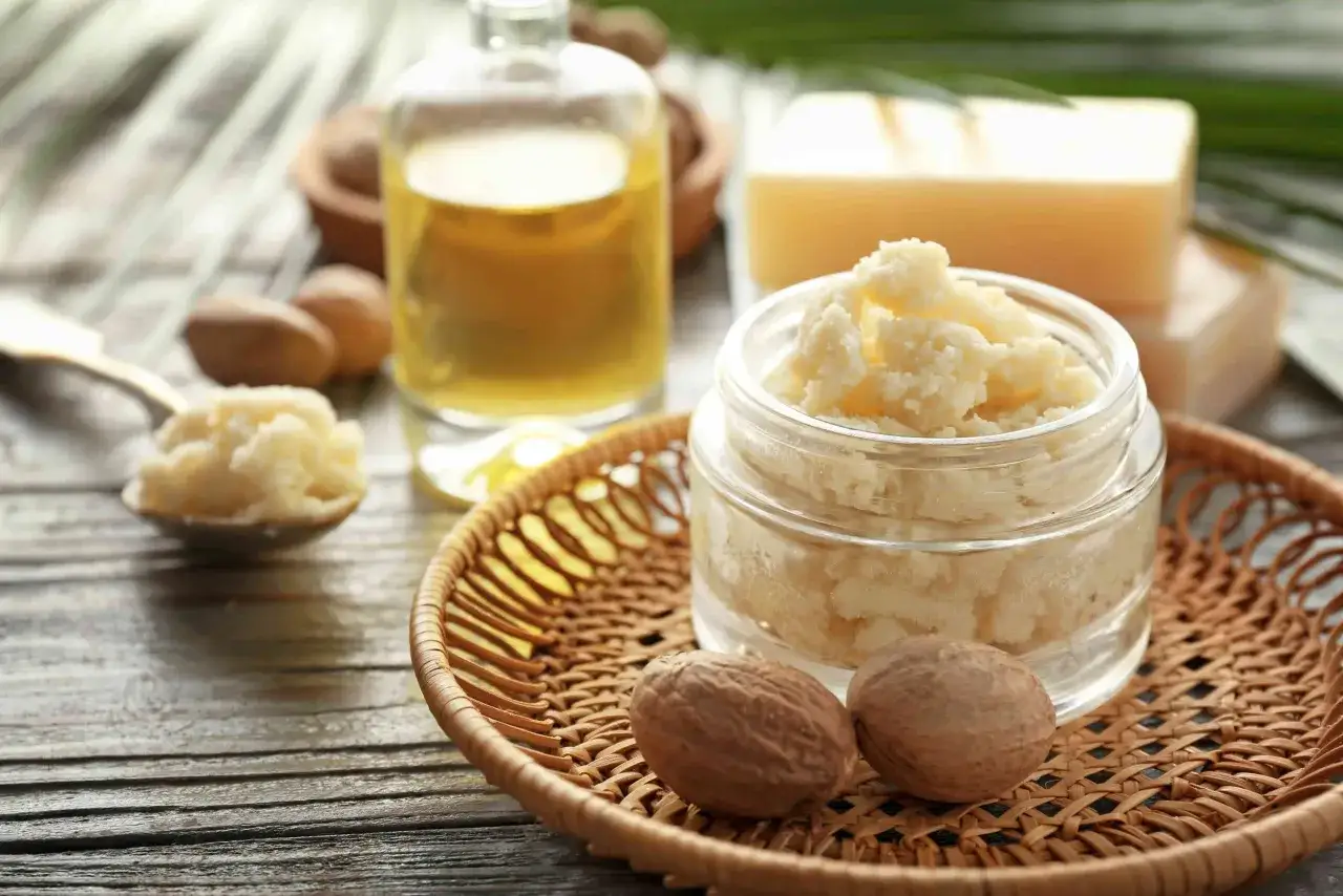 Un pot de beurre de karit&eacute;, id&eacute;al pour les cheveux boucl&eacute;s, avec des noix et une huile dor&eacute;e.
