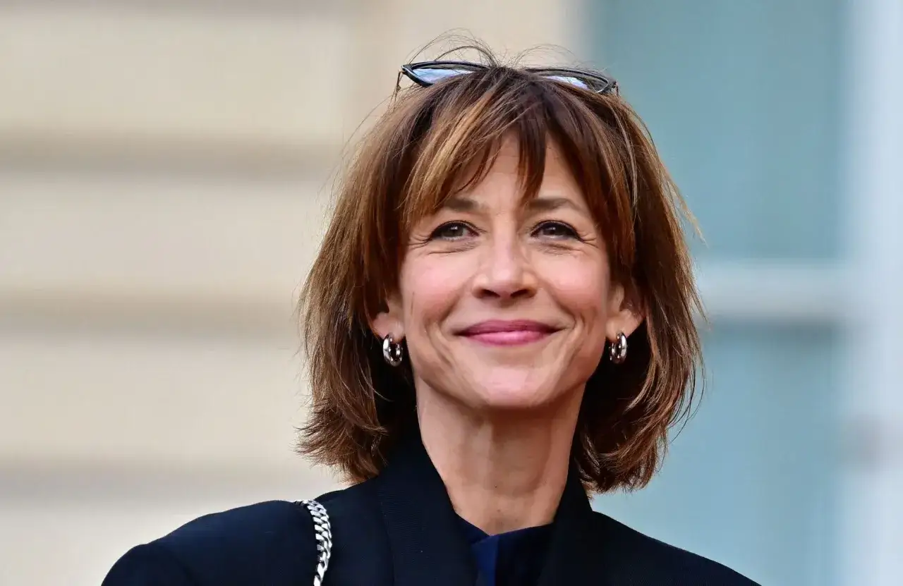 Un sourire radieux pour ce modèle de coiffure aux cheveux châtains courts et dégradés, avec des lunettes perchées sur la tête.