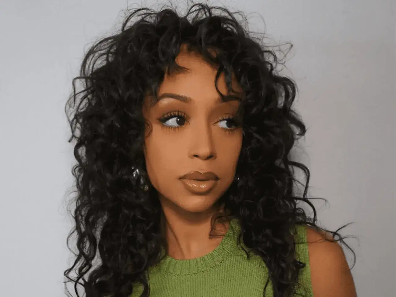 Une femme au regard intense arbore une magnifique boucle anglaise, ses cheveux sombres et ondulés encadrant son visage.