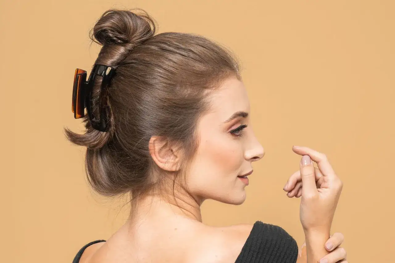 Coiffure chic avec une pince à cheveux marron retenant un chignon élégant.