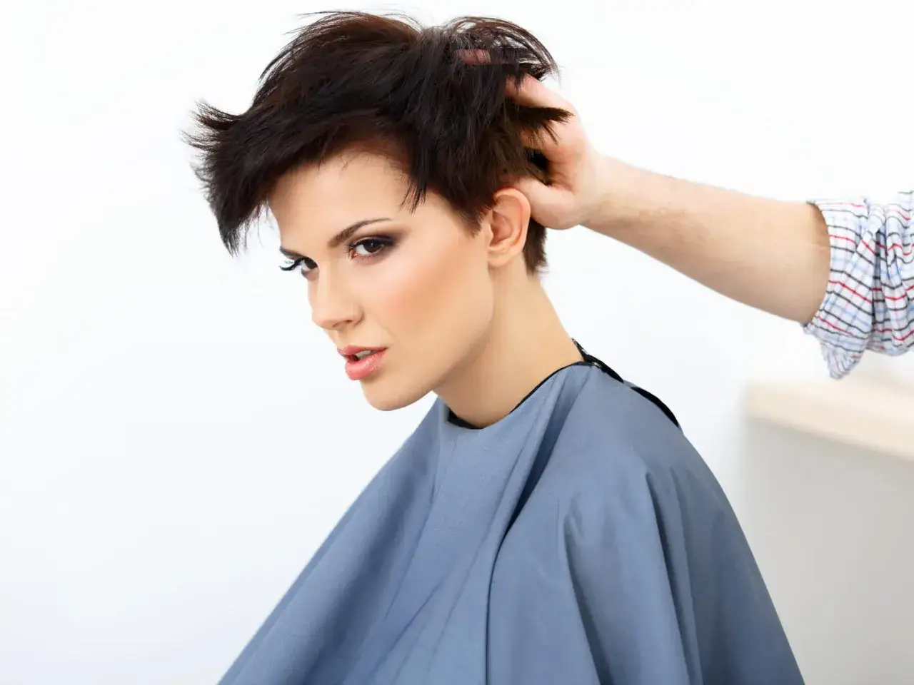 Une femme arbore une coiffure rock femme court, ses cheveux sombres sont coiff&eacute;s avec audace.