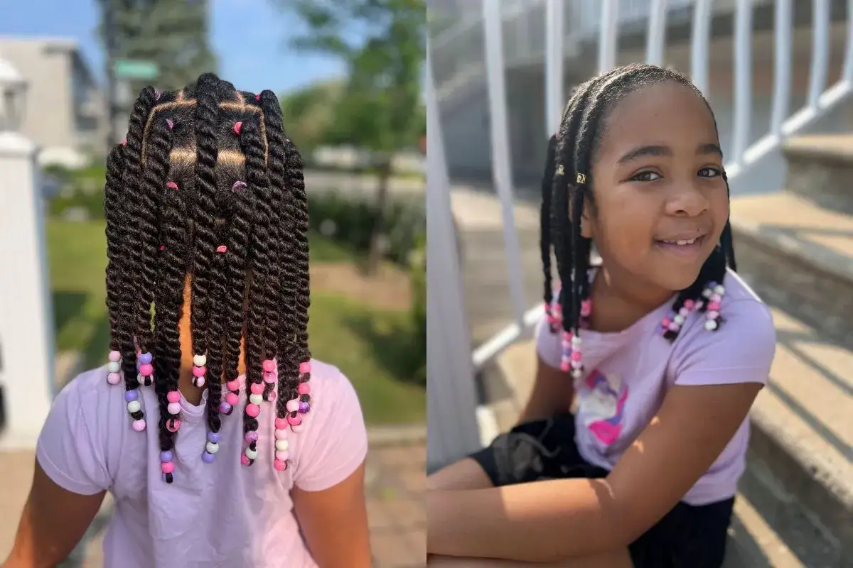 Une jeune fille aux cheveux bouclés, coiffés en torsades ornées de perles colorées, sourit joyeusement.