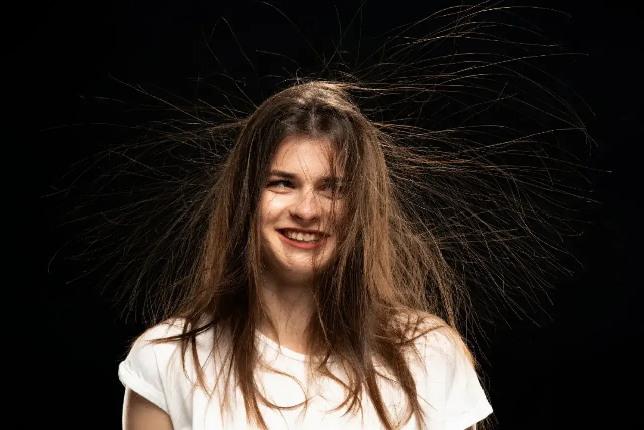 Cheveux &eacute;lectriques en hiver, une jeune femme au sourire espi&egrave;gle, ses m&egrave;ches s'envolent comme par magie.