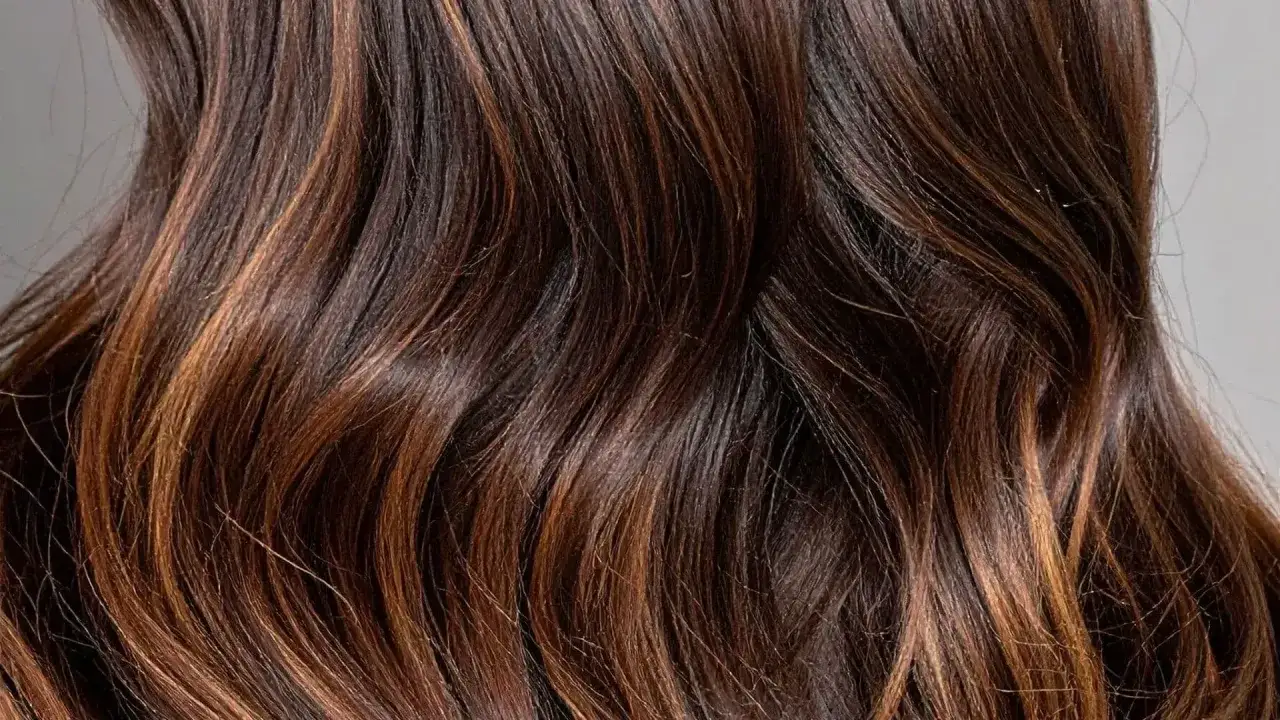 Chevelure brune aux reflets chauds, un ombré hair subtil qui capte la lumière.