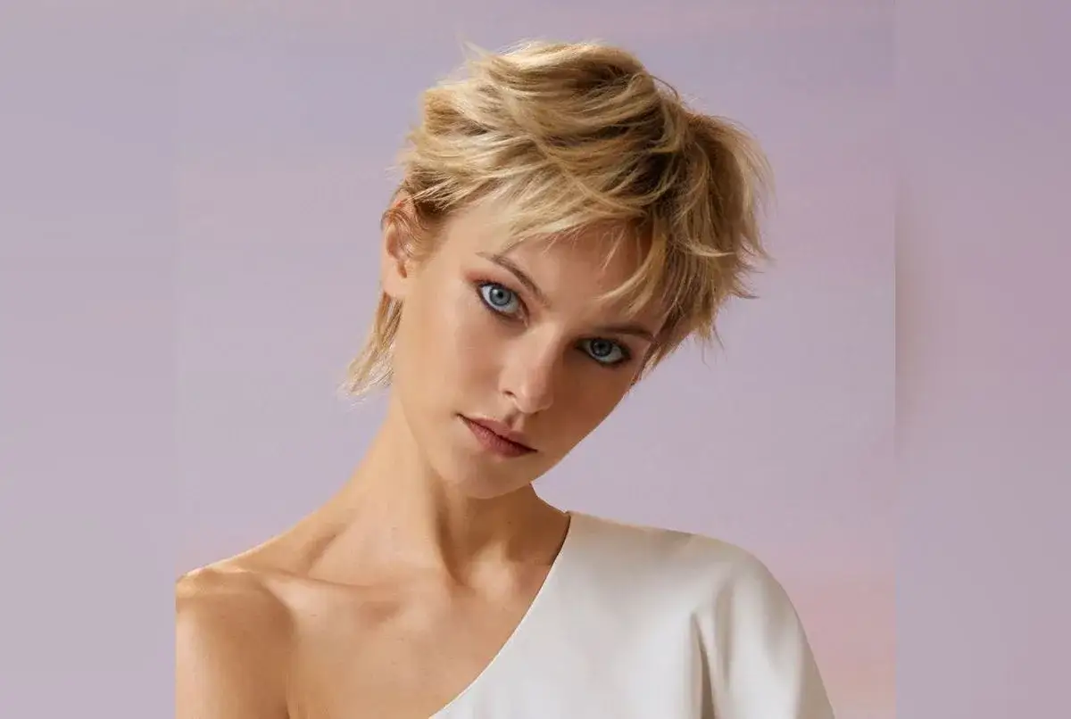 Une jeune femme au regard intense arbore une coupe de cheveux court effilé sauvage, accentuant son style audacieux.