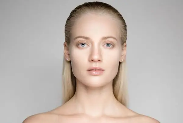 Portrait d'une jeune femme aux yeux bleus et aux cheveux gominés, mise en valeur par une lumière douce.